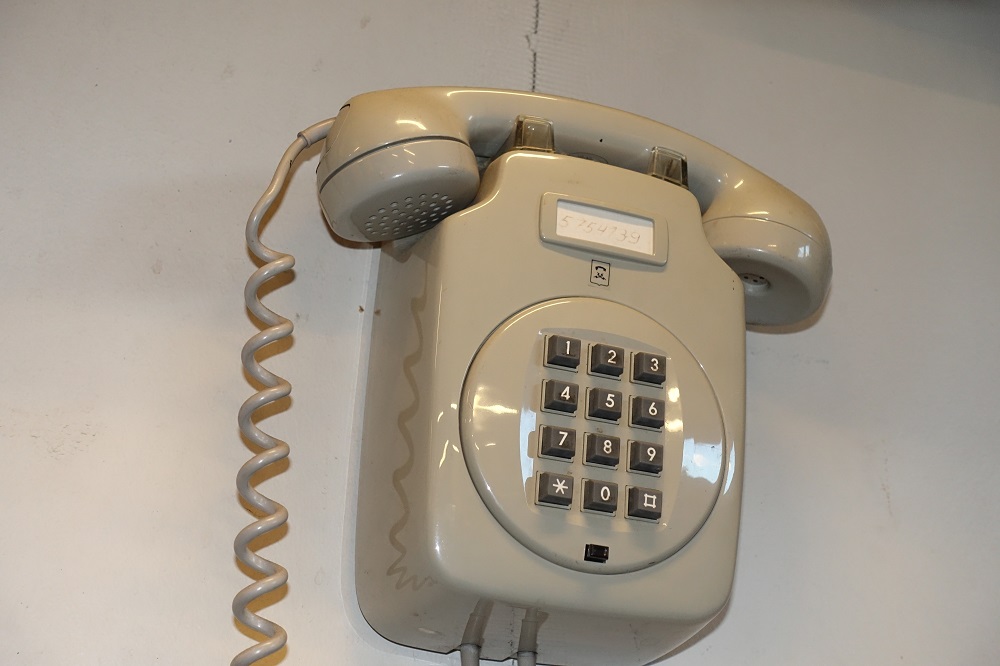 En gammal tråd telefon monterad på väggen.